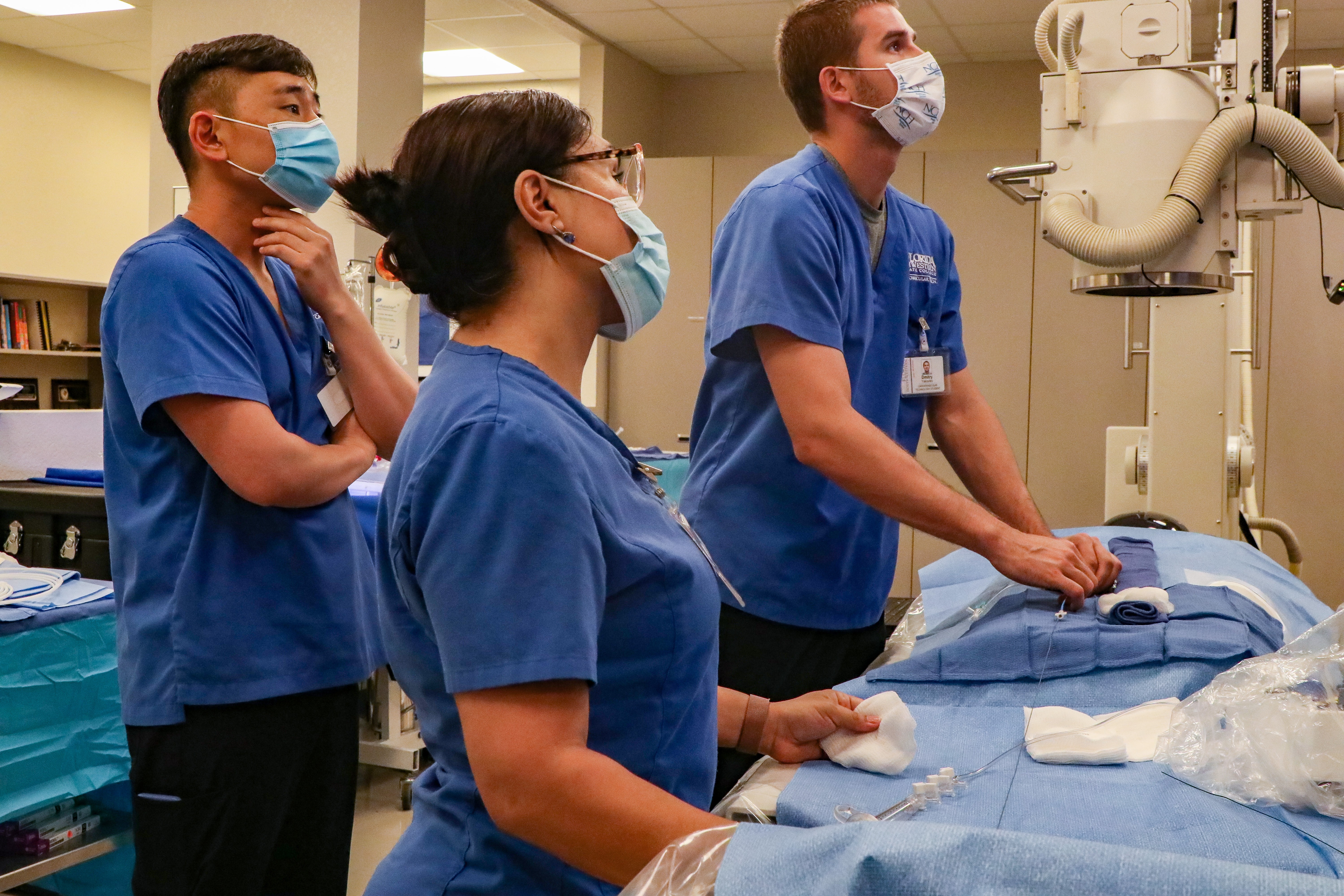 Image of FSW students looking at cardiovascular imaging and heat data on a large monitor during a clinical simulation.