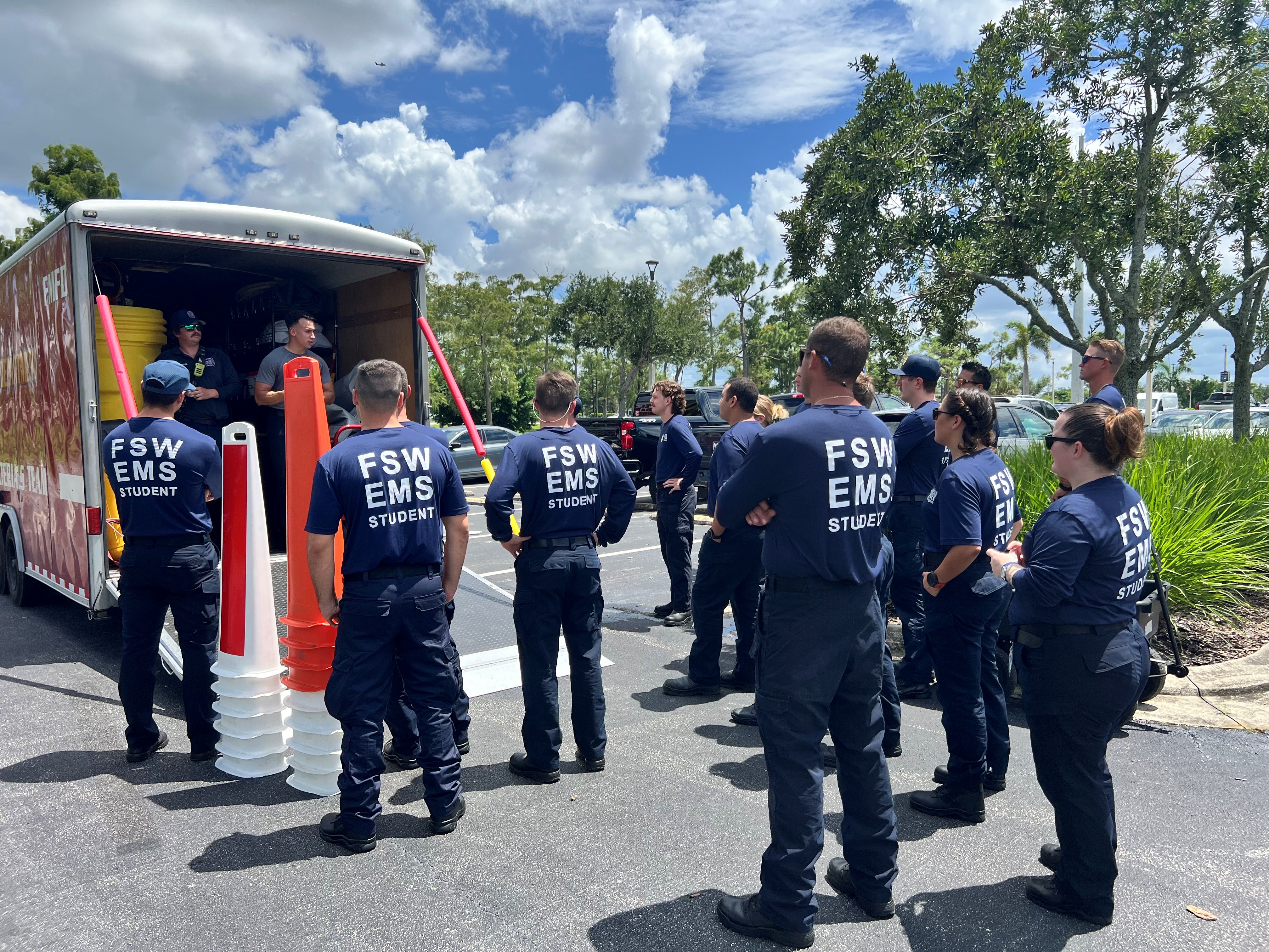 EMS students standing in front of a training trailer receiving instruction