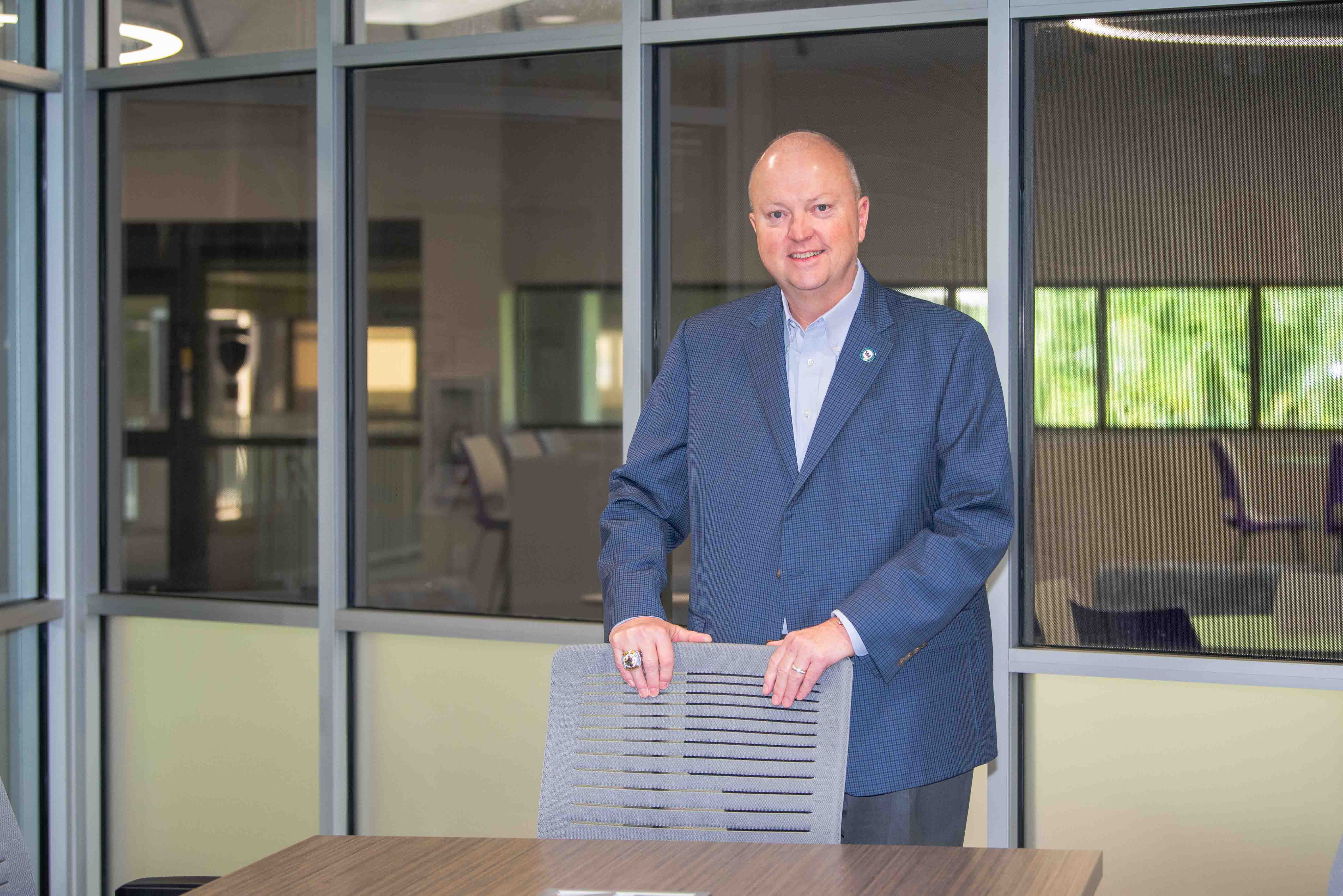 FSW President Dr. Jeff Allbritten standing behind a chair and smiling.
