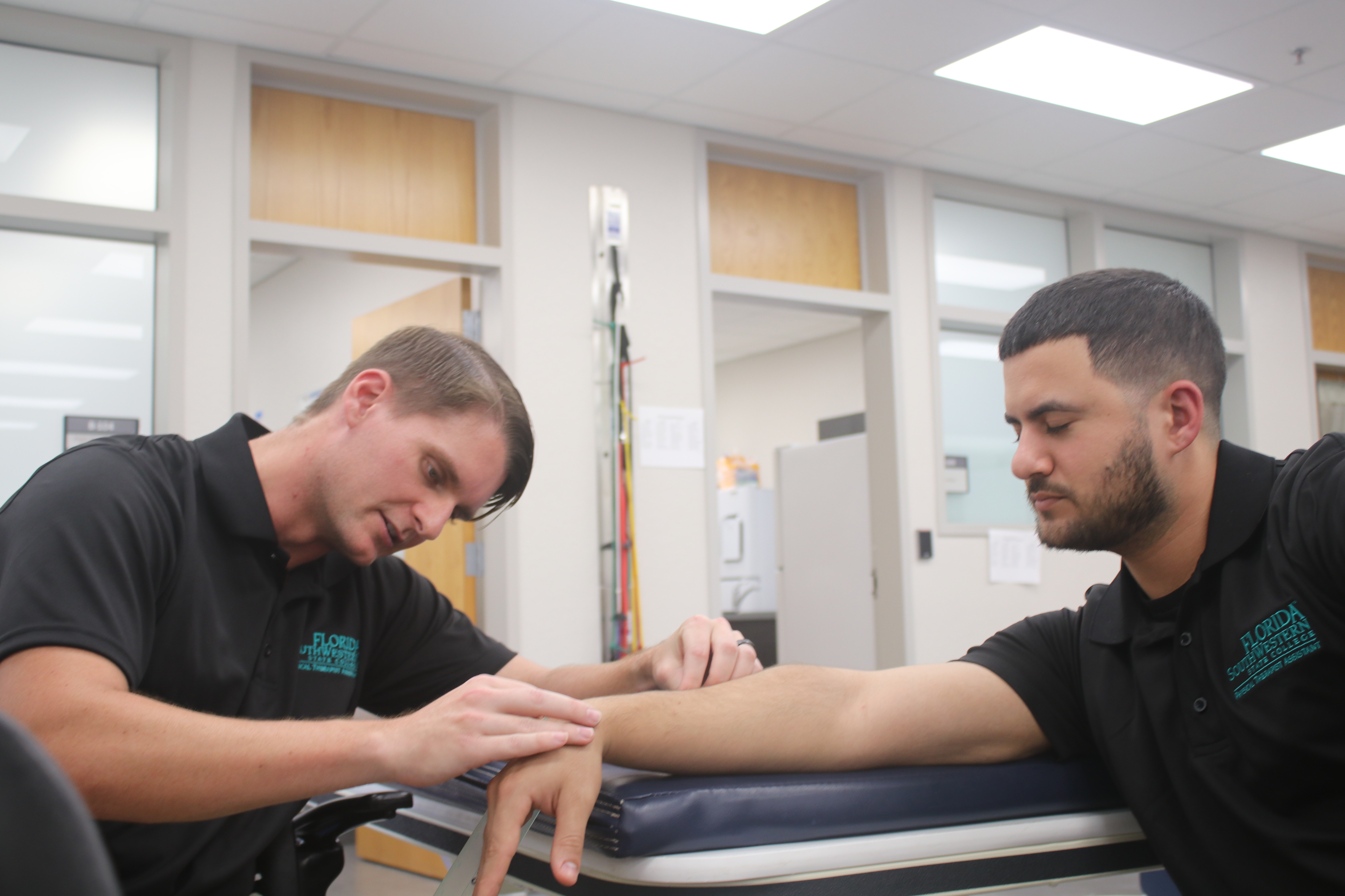 Two FSW Physical Therapist Assistant students practice assessing wrist movement in a classroom lab.