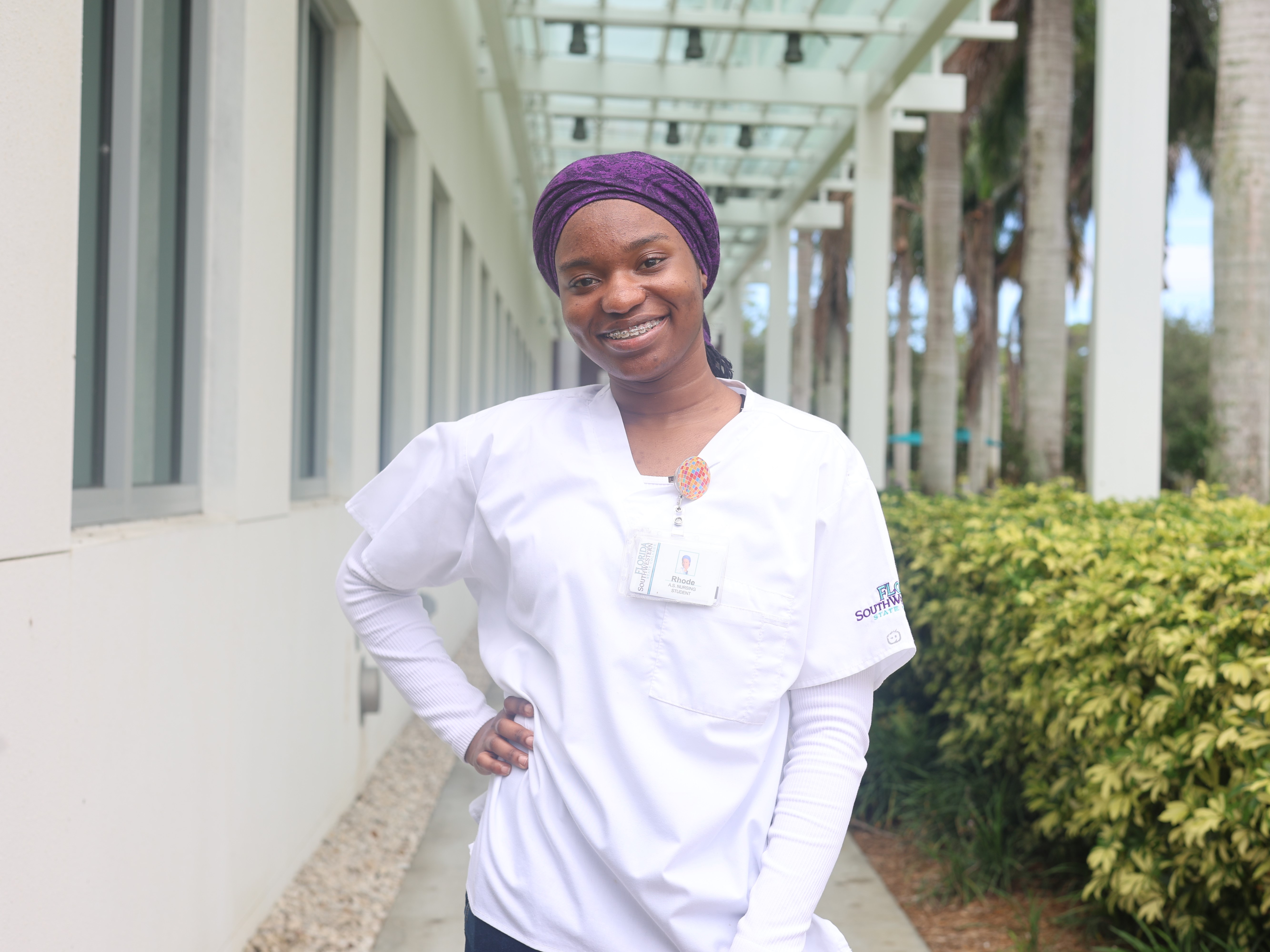 FSW student Rhode C. standing in front of Building N on the Collier Campus, wearing nursing scrub.