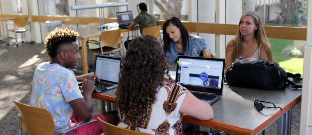 �鶹Ů�� Students siting in a group while studying in the Library.
