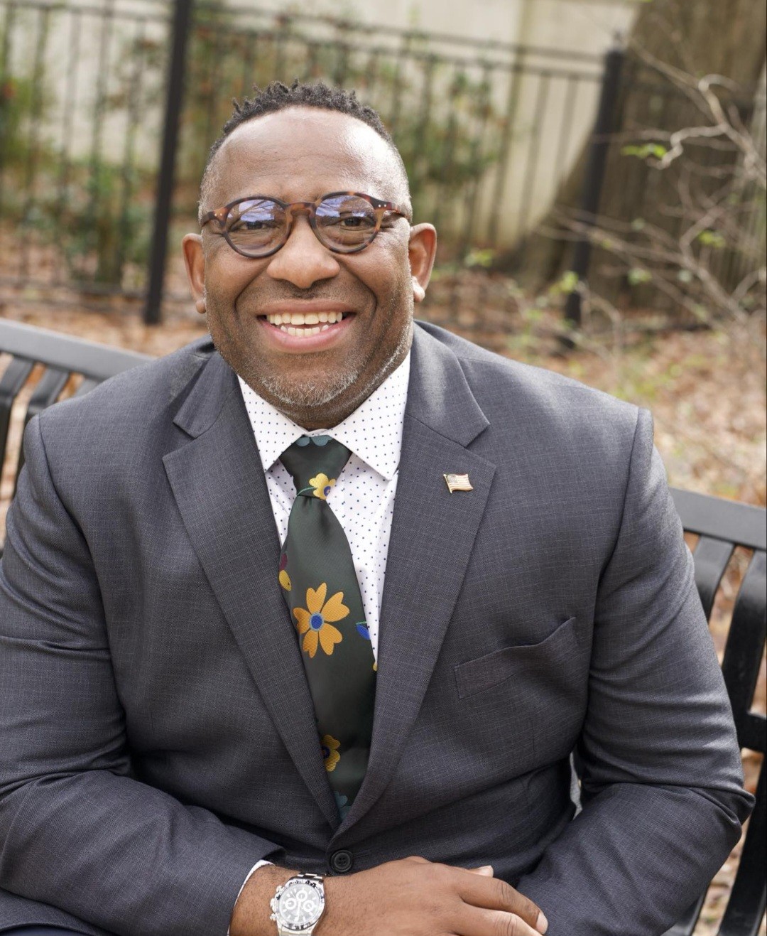 Headshot of a smiling FSW Trustee Dewayne Moore, DPT, seated on a bench outdoors.